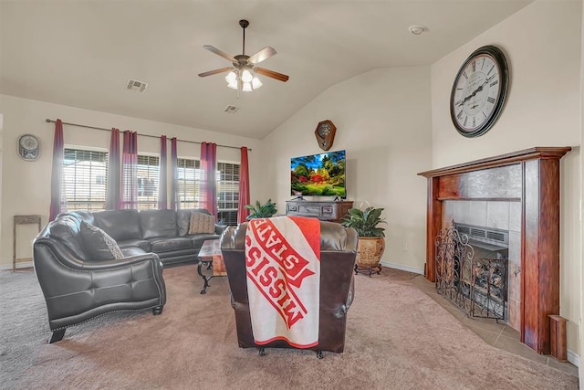 carpeted living room with ceiling fan, lofted ceiling, and a tiled fireplace