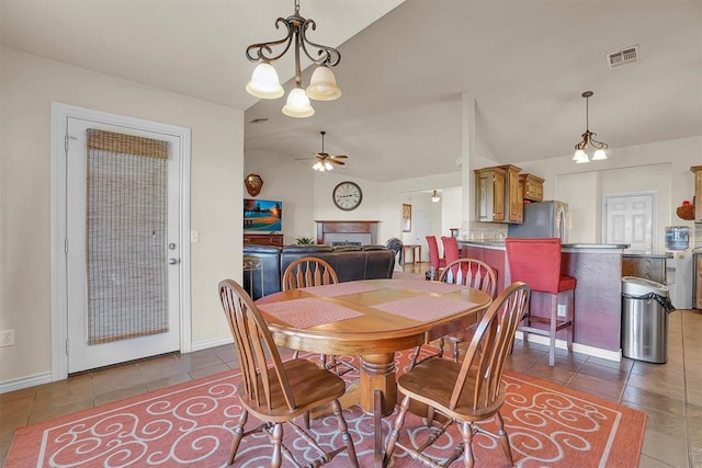 tiled dining space featuring ceiling fan with notable chandelier and lofted ceiling