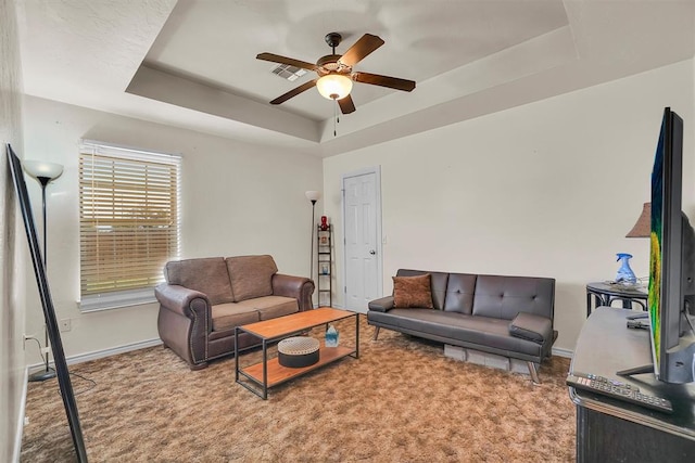 living room with carpet flooring, a raised ceiling, and ceiling fan