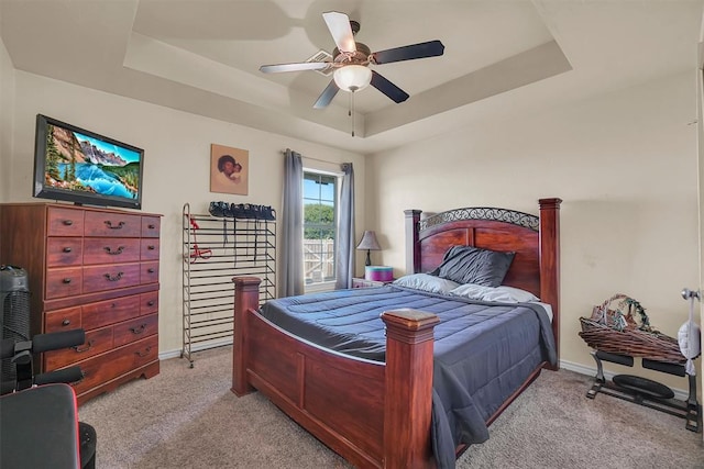 carpeted bedroom featuring a raised ceiling and ceiling fan