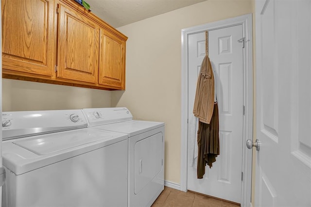 laundry area with washing machine and clothes dryer, light tile patterned floors, and cabinets