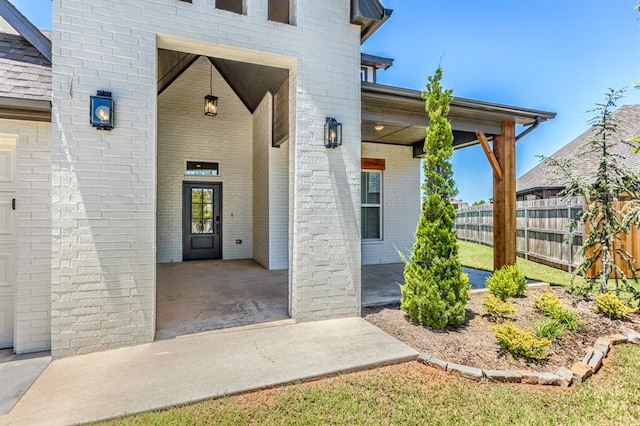 property entrance featuring fence and brick siding