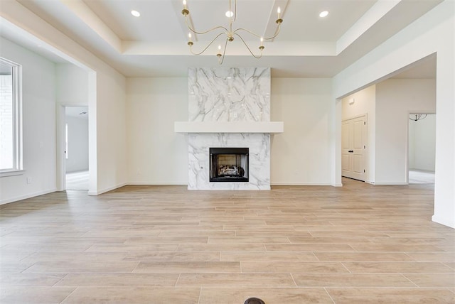 2405 Crystal Creek Dr, Yukon, OK 73099 - unfurnished living room with a raised ceiling, light wood-style flooring, a chandelier, a premium fireplace, and recessed lighting