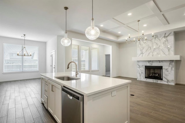 kitchen featuring dishwasher, hanging light fixtures, coffered ceiling, a premium fireplace, and an island with sink