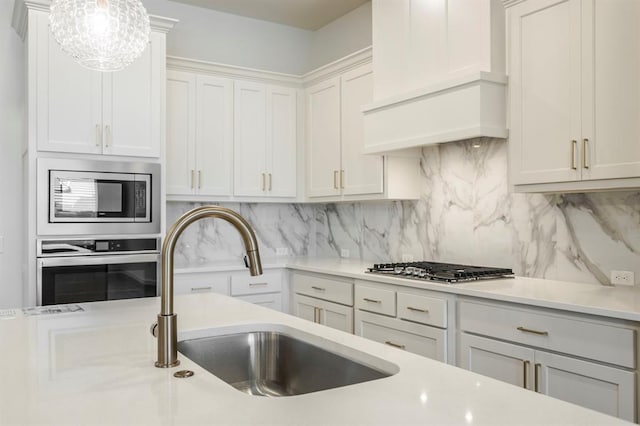 kitchen featuring backsplash, sink, decorative light fixtures, white cabinetry, and stainless steel appliances