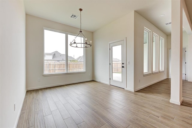 unfurnished dining area featuring light hardwood / wood-style flooring and a chandelier