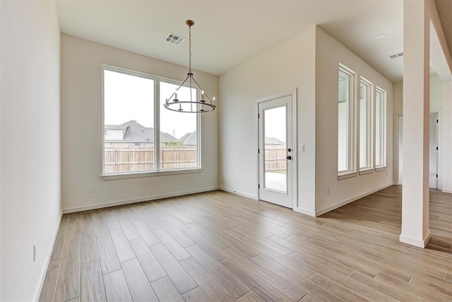 2405 Crystal Creek Dr, Yukon, OK 73099 - unfurnished dining area with a chandelier, healthy amount of natural light, and light wood-style flooring