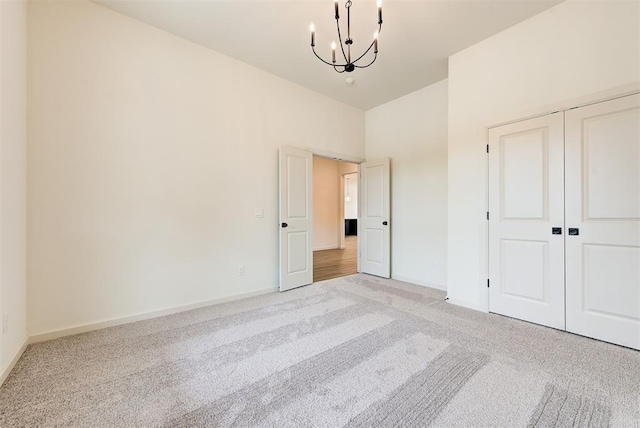 unfurnished bedroom featuring a closet, light colored carpet, and an inviting chandelier