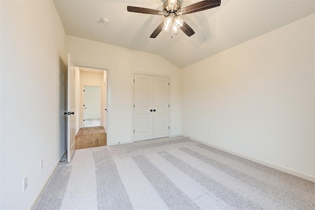 unfurnished bedroom with a closet, light colored carpet, vaulted ceiling, and ceiling fan