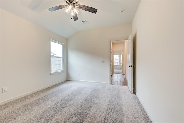 carpeted spare room with ceiling fan and vaulted ceiling