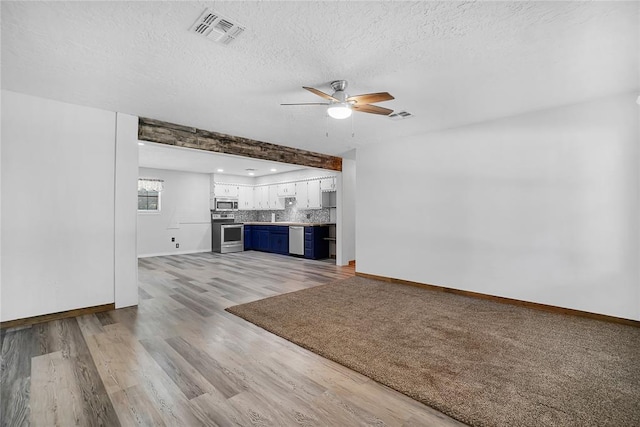 unfurnished living room featuring light wood-type flooring, a textured ceiling, and ceiling fan