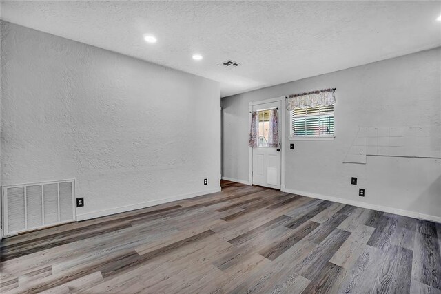 spare room featuring light hardwood / wood-style floors and a textured ceiling