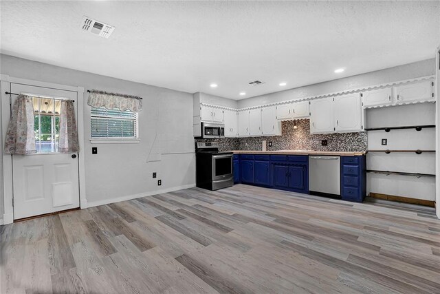 kitchen with blue cabinetry, stainless steel appliances, backsplash, white cabinets, and light wood-type flooring