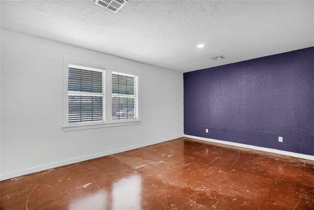 empty room with a textured ceiling and concrete floors