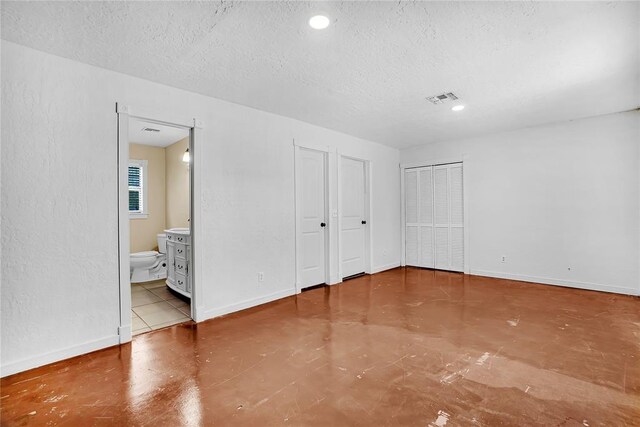 unfurnished bedroom featuring connected bathroom and a textured ceiling