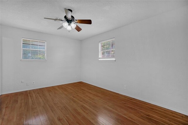 spare room with hardwood / wood-style floors, a healthy amount of sunlight, and a textured ceiling