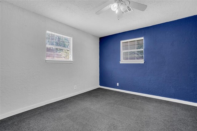 unfurnished room featuring a textured ceiling, dark carpet, and ceiling fan