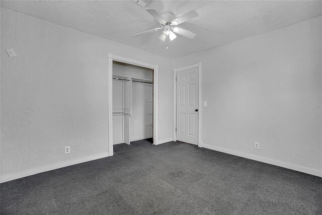 unfurnished bedroom with dark colored carpet, ceiling fan, a textured ceiling, and a closet