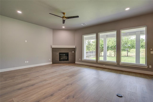 unfurnished living room with ceiling fan, light hardwood / wood-style floors, and a brick fireplace