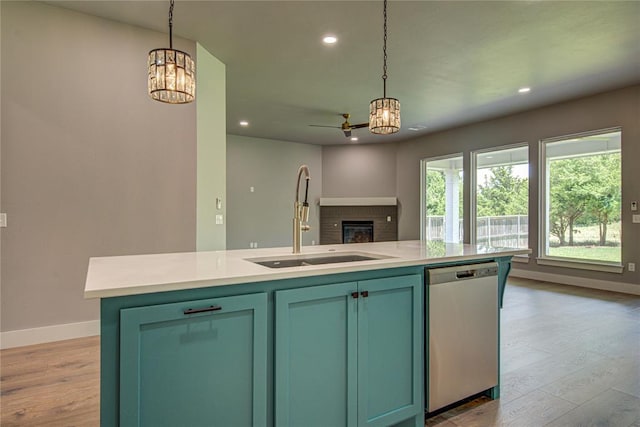 kitchen featuring sink, stainless steel dishwasher, light hardwood / wood-style floors, decorative light fixtures, and a center island with sink