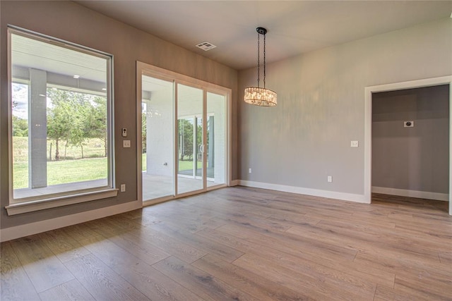 unfurnished dining area featuring a notable chandelier and light hardwood / wood-style floors