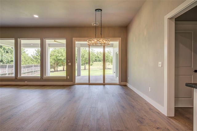 doorway to outside with hardwood / wood-style floors and ceiling fan with notable chandelier