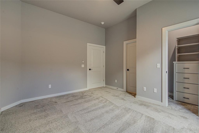 unfurnished bedroom with a spacious closet, light carpet, and a closet