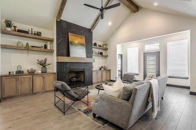 living room featuring ceiling fan, light hardwood / wood-style flooring, a high end fireplace, beamed ceiling, and high vaulted ceiling