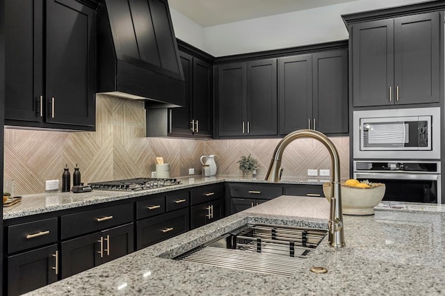 kitchen featuring light stone countertops, custom range hood, stainless steel appliances, and tasteful backsplash