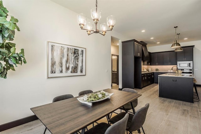 dining area featuring sink, a chandelier, and light wood-type flooring