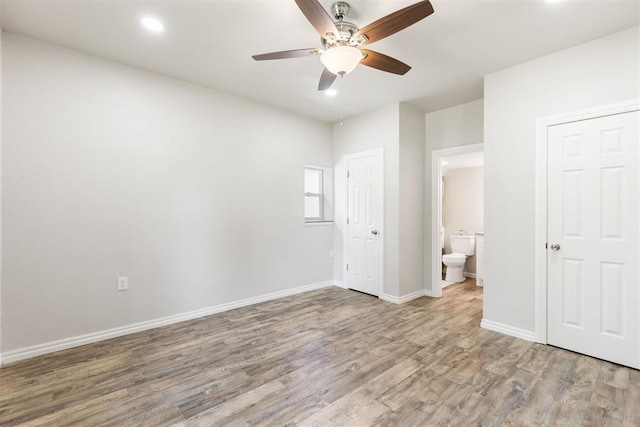 unfurnished bedroom with ceiling fan, wood-type flooring, and connected bathroom