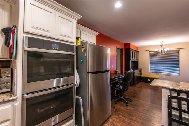 kitchen featuring white cabinets, stainless steel appliances, an inviting chandelier, and dark hardwood / wood-style floors