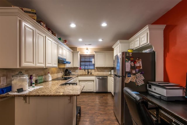 kitchen featuring kitchen peninsula, appliances with stainless steel finishes, a breakfast bar, sink, and white cabinets