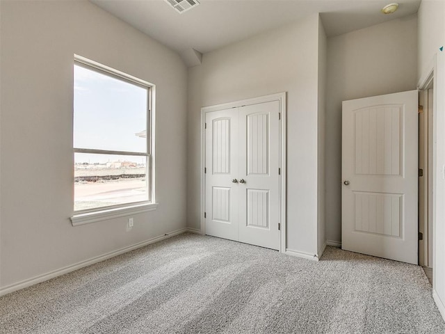 unfurnished bedroom with light colored carpet and a closet