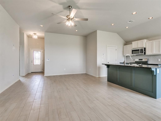 kitchen featuring white cabinets, lofted ceiling, light wood-type flooring, and stainless steel appliances