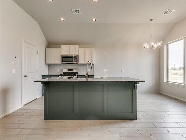 kitchen with white cabinetry, stainless steel appliances, dark stone counters, a chandelier, and vaulted ceiling