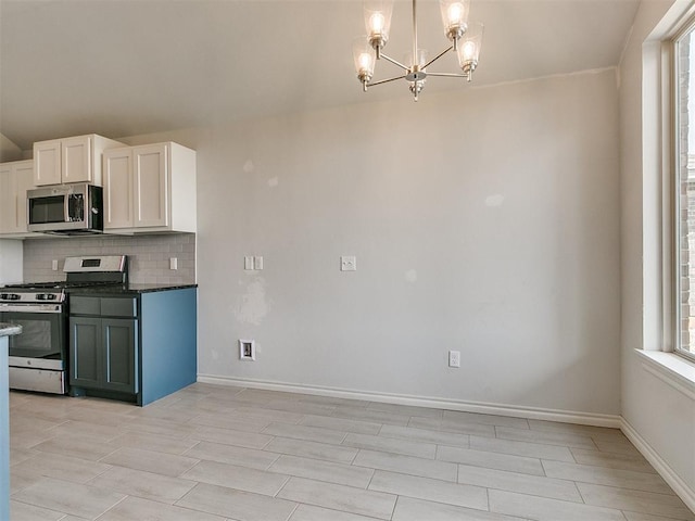 kitchen featuring backsplash, stainless steel appliances, a notable chandelier, white cabinets, and hanging light fixtures