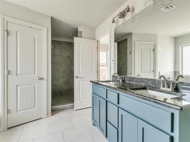 bathroom with tile patterned flooring, vanity, tiled shower, and plenty of natural light