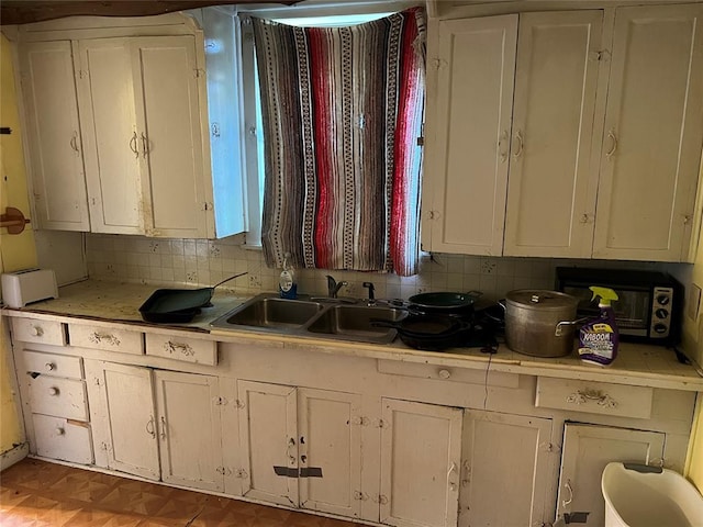 kitchen with white cabinets, decorative backsplash, sink, and light parquet floors