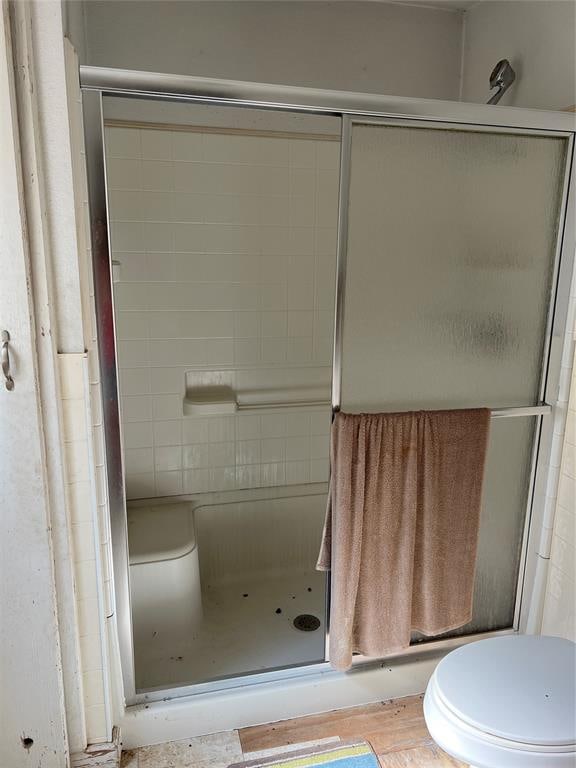 bathroom featuring toilet and a shower with door