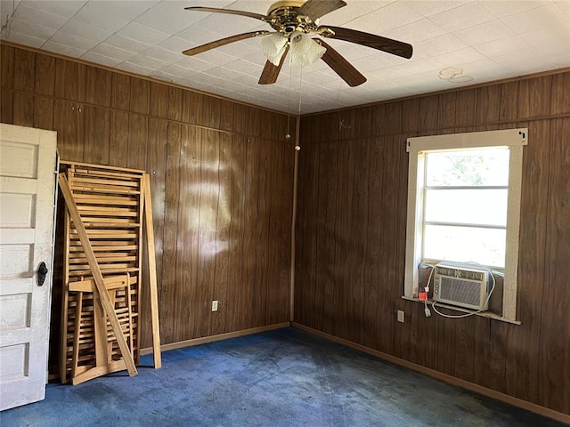 carpeted spare room with cooling unit, wooden walls, and ceiling fan