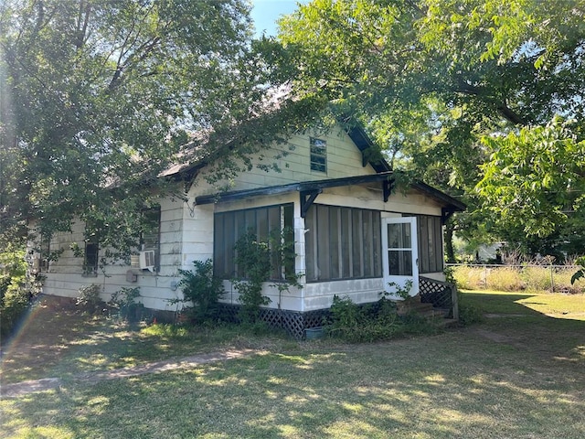 view of front of home with a front lawn, cooling unit, and a sunroom