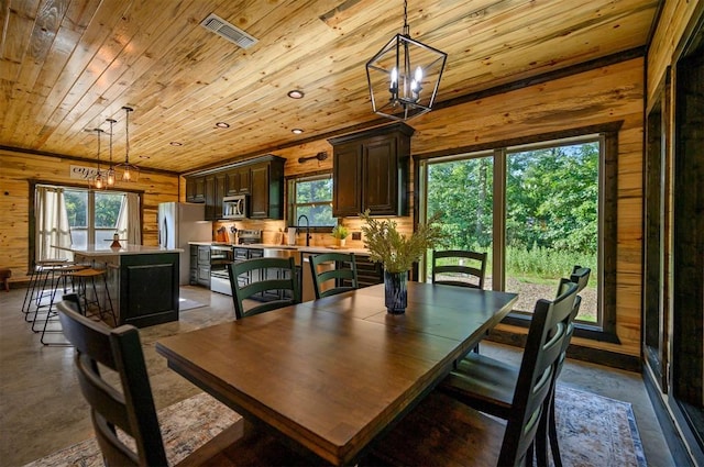 dining area featuring wooden walls, a chandelier, and wooden ceiling