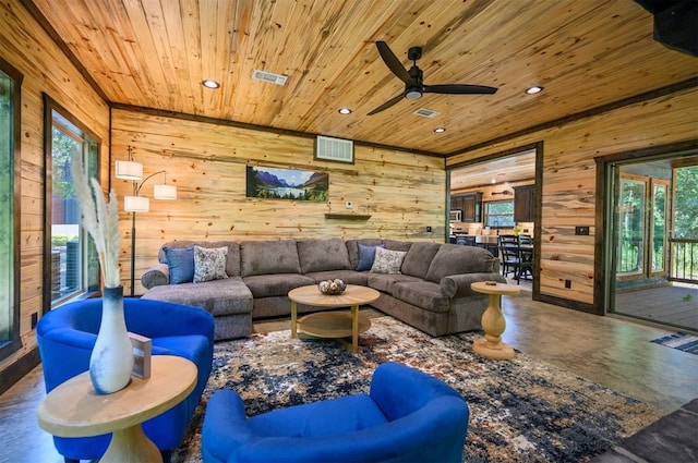 living room with ceiling fan, wooden ceiling, wooden walls, and concrete floors