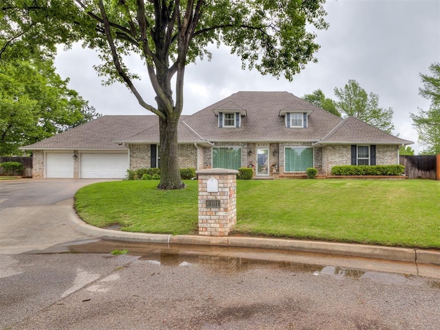 view of front of property with fence, driveway, a front lawn, and brick siding
