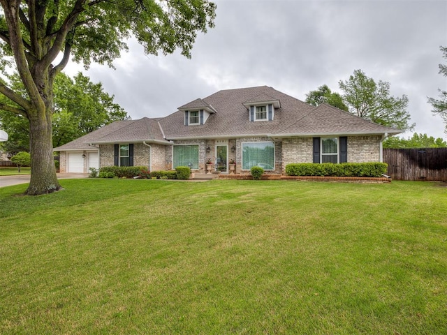 view of front of home featuring a front yard, brick siding, fence, an attached garage, and a shingled roof