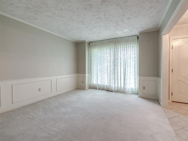 tiled spare room featuring crown molding, a textured ceiling, wainscoting, and a decorative wall