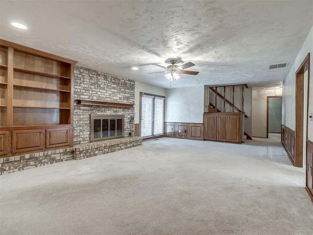 unfurnished living room featuring ceiling fan, visible vents, light carpet, and stairway