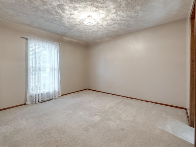empty room featuring a textured ceiling, baseboards, and light carpet