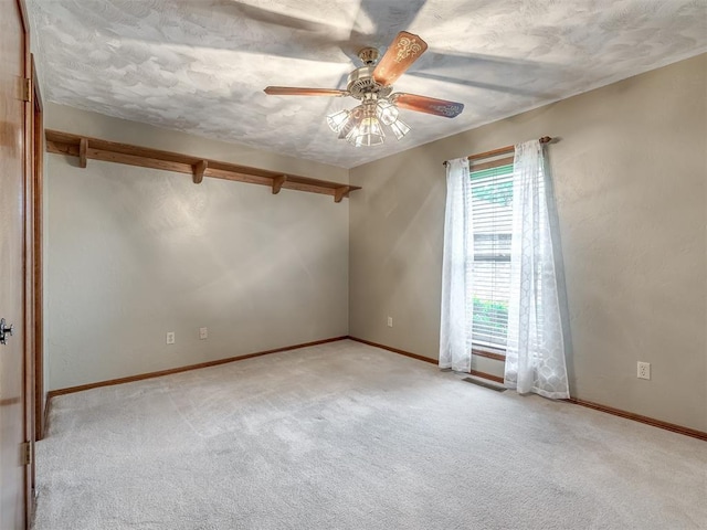 empty room featuring carpet flooring, a ceiling fan, and baseboards